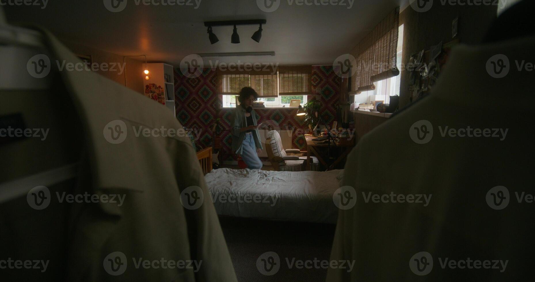 A woman is standing in a bedroom with a bed and a dresser photo