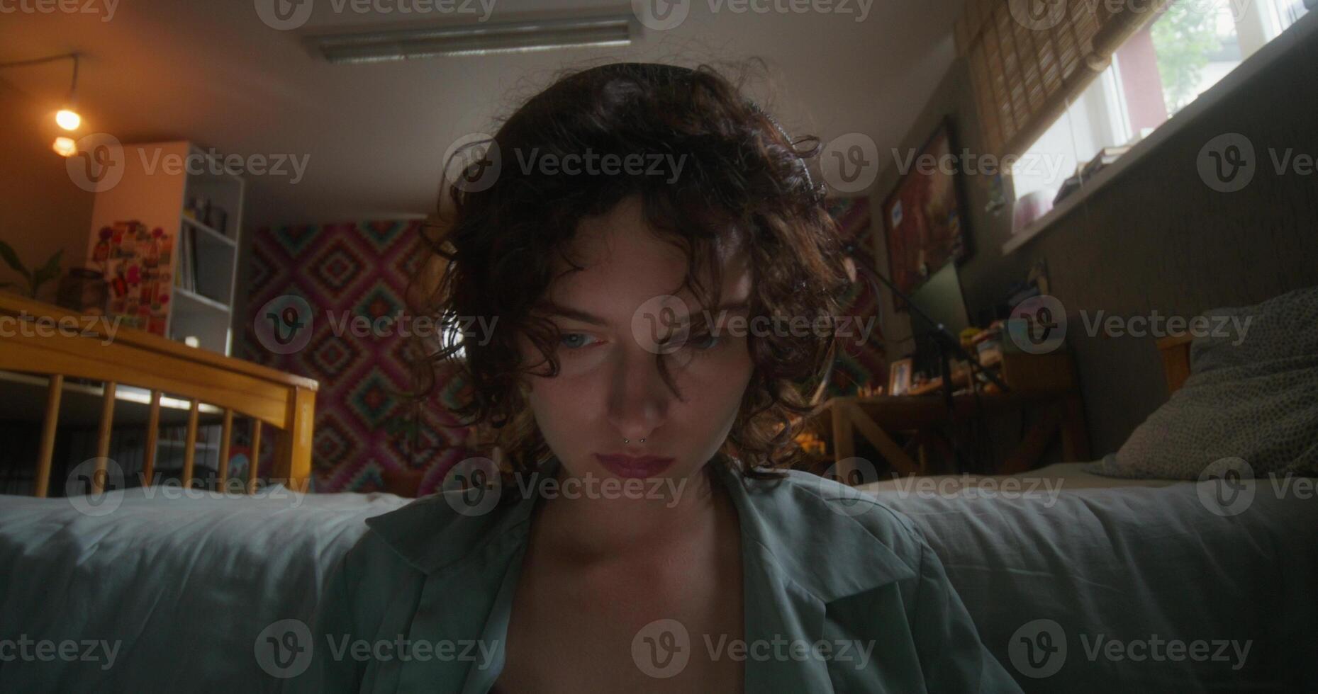 A woman with curly hair sitting on a bed photo