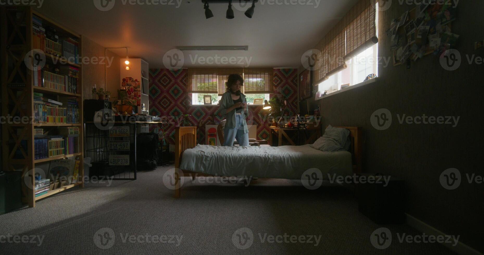 A woman standing in a bedroom with a bed and a desk photo