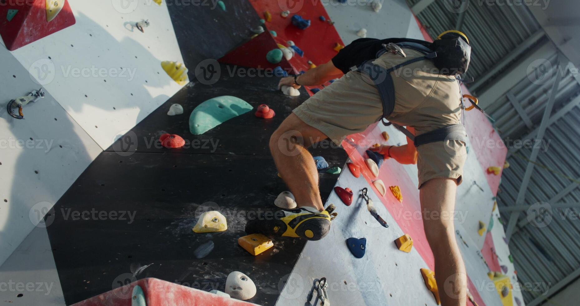 A young man equipped with climbing harnesses goes down the climbing wall photo