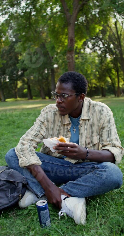 A man eats a burger in the park photo