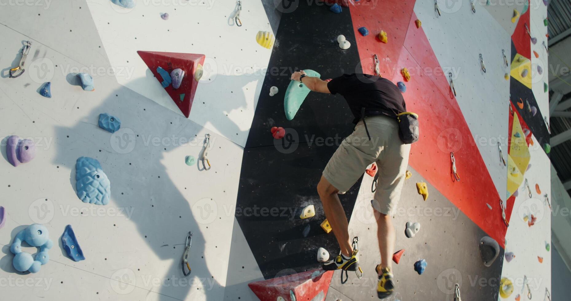 A young man goes down the climbing wall without safety ropes photo