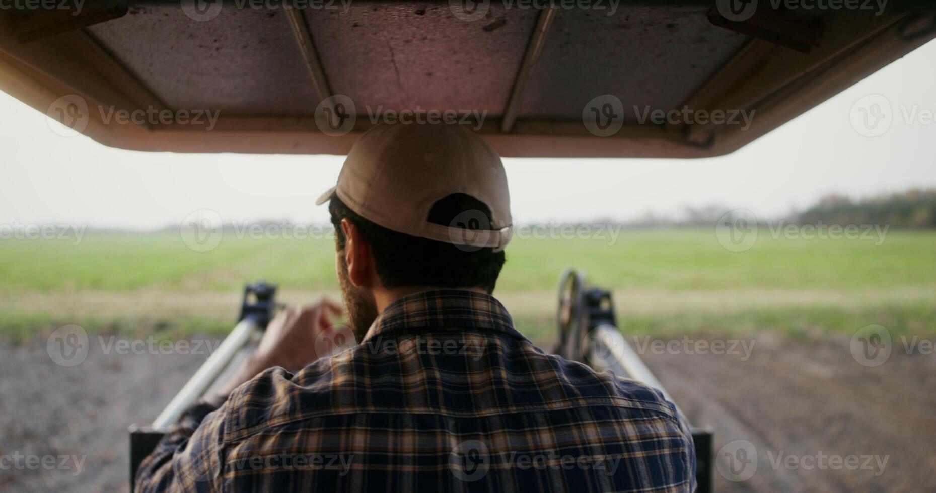 Close-up rear view of a tractor driver sitting at the wheel of an machine photo