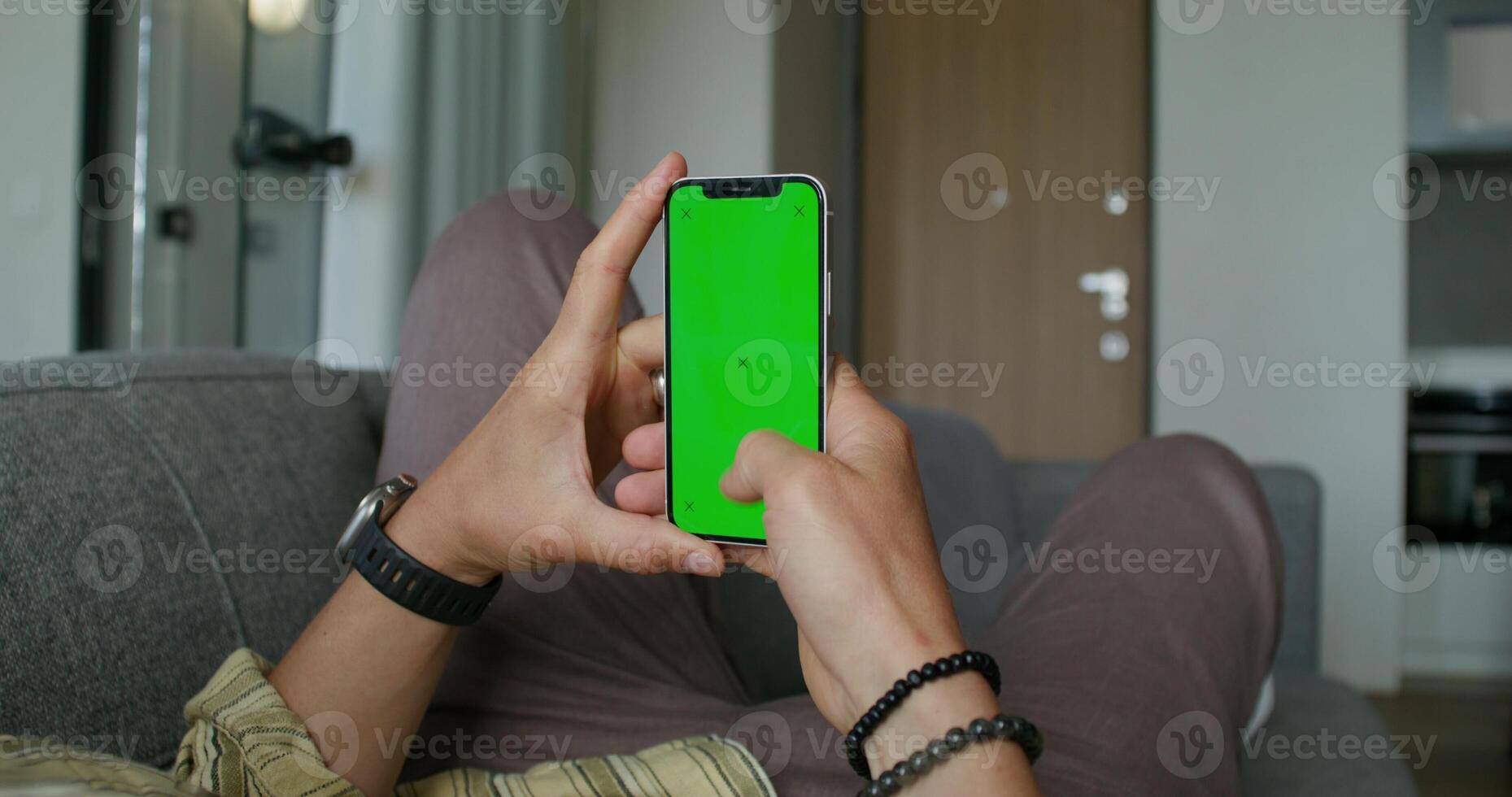 A man is sitting on a couch with a green screen photo