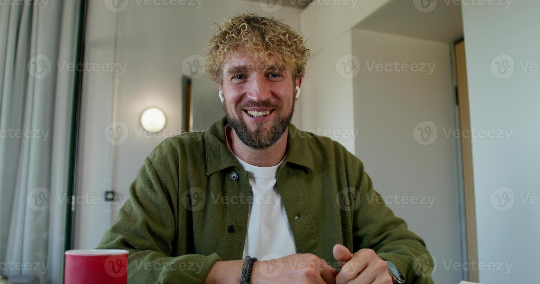 A man with a beard sitting at a table with a red cup photo