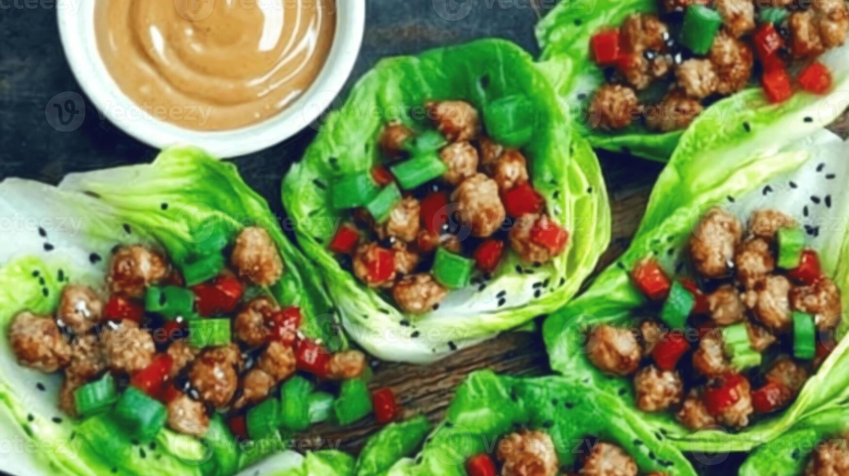 A platter of lettuce wraps filled with meat and vegetables, served with a dipping sauce. photo