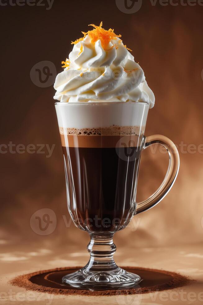 A delicious coffee drink topped with whipped cream and orange zest in a clear glass mug. photo