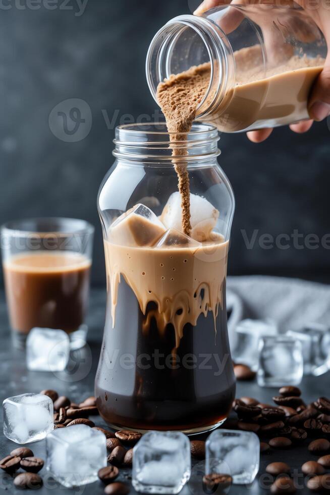 A hand pours coffee powder into a jar with iced coffee and coffee beans on a dark surface. photo