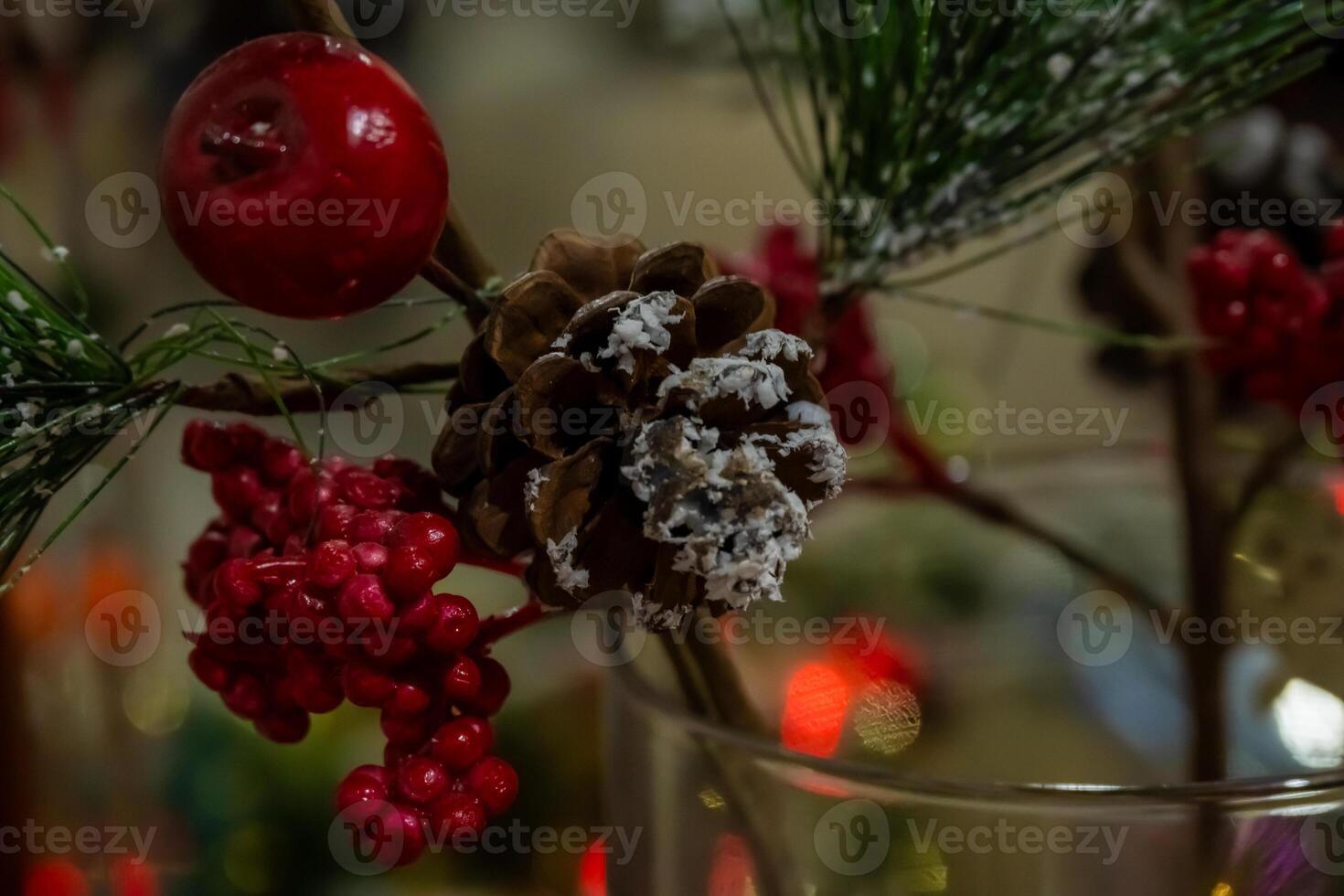 A vase with red berries and pine cones photo