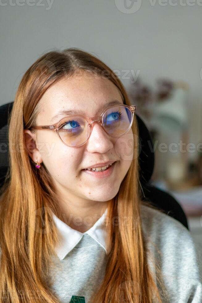 A girl with glasses and a grey sweater sitting in front of a computer photo