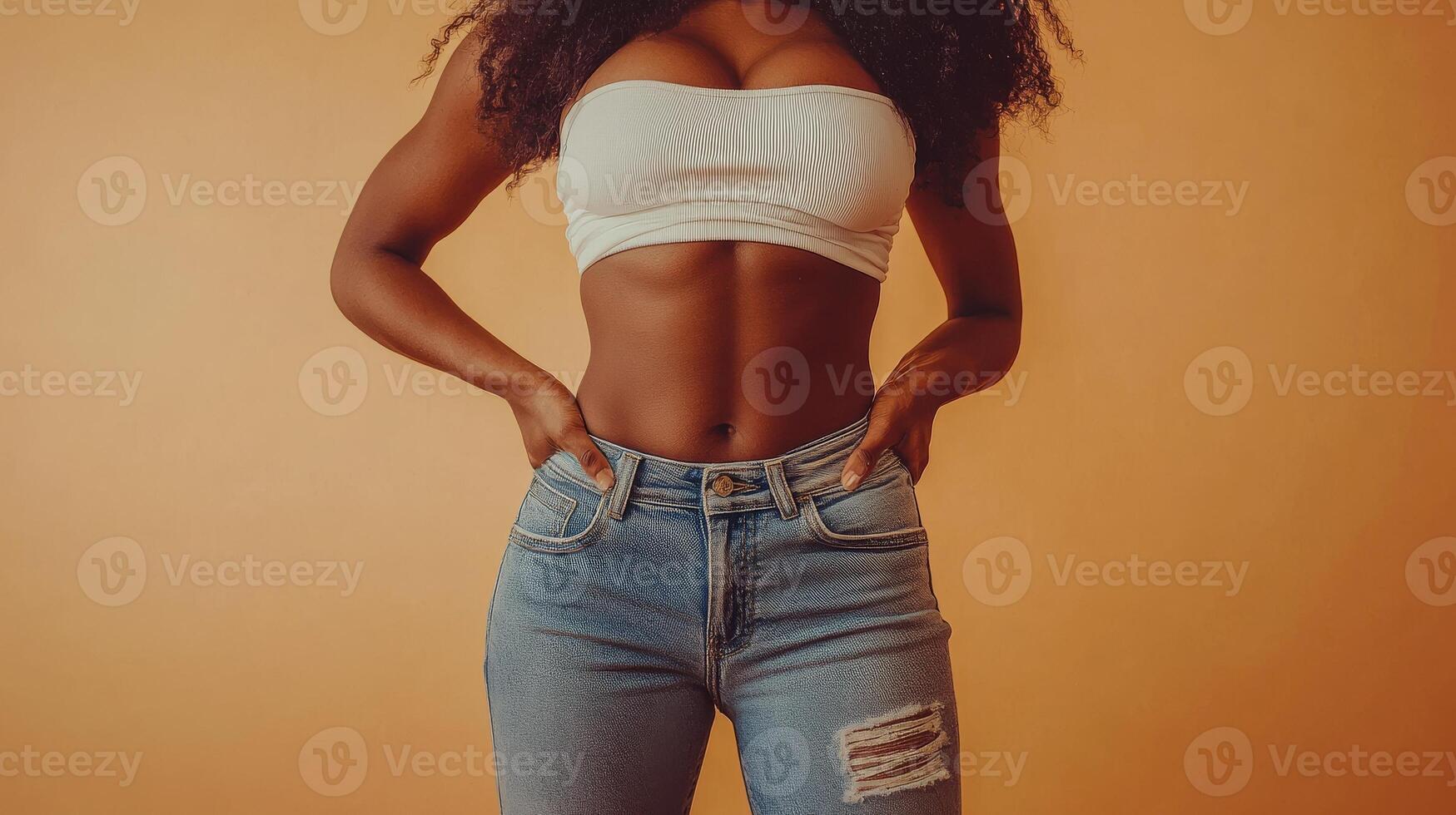 Confident young african female in white top and jeans against orange background photo