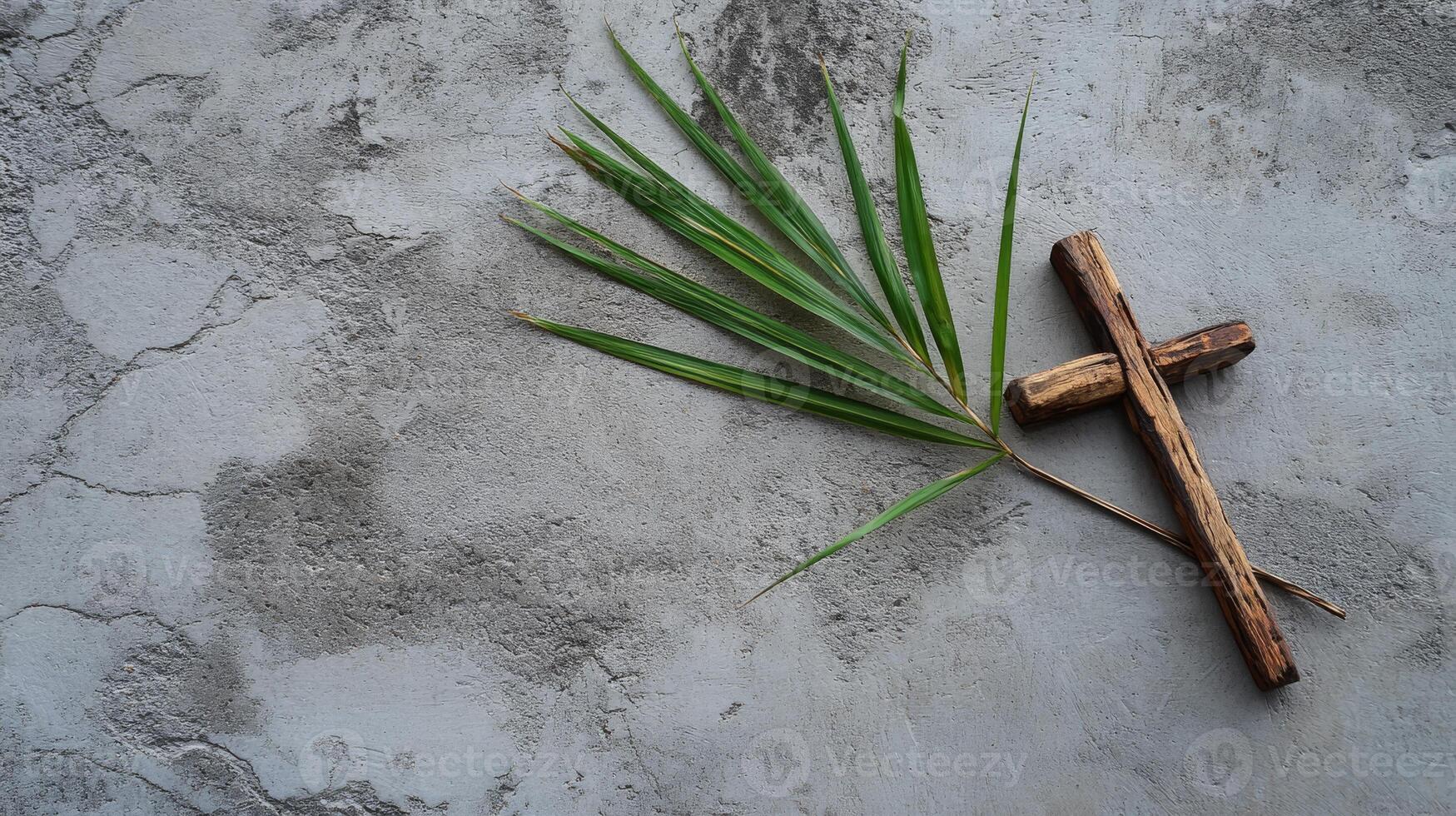 Wooden cross and palm leaf on concrete surface symbolizing christianity and peace photo