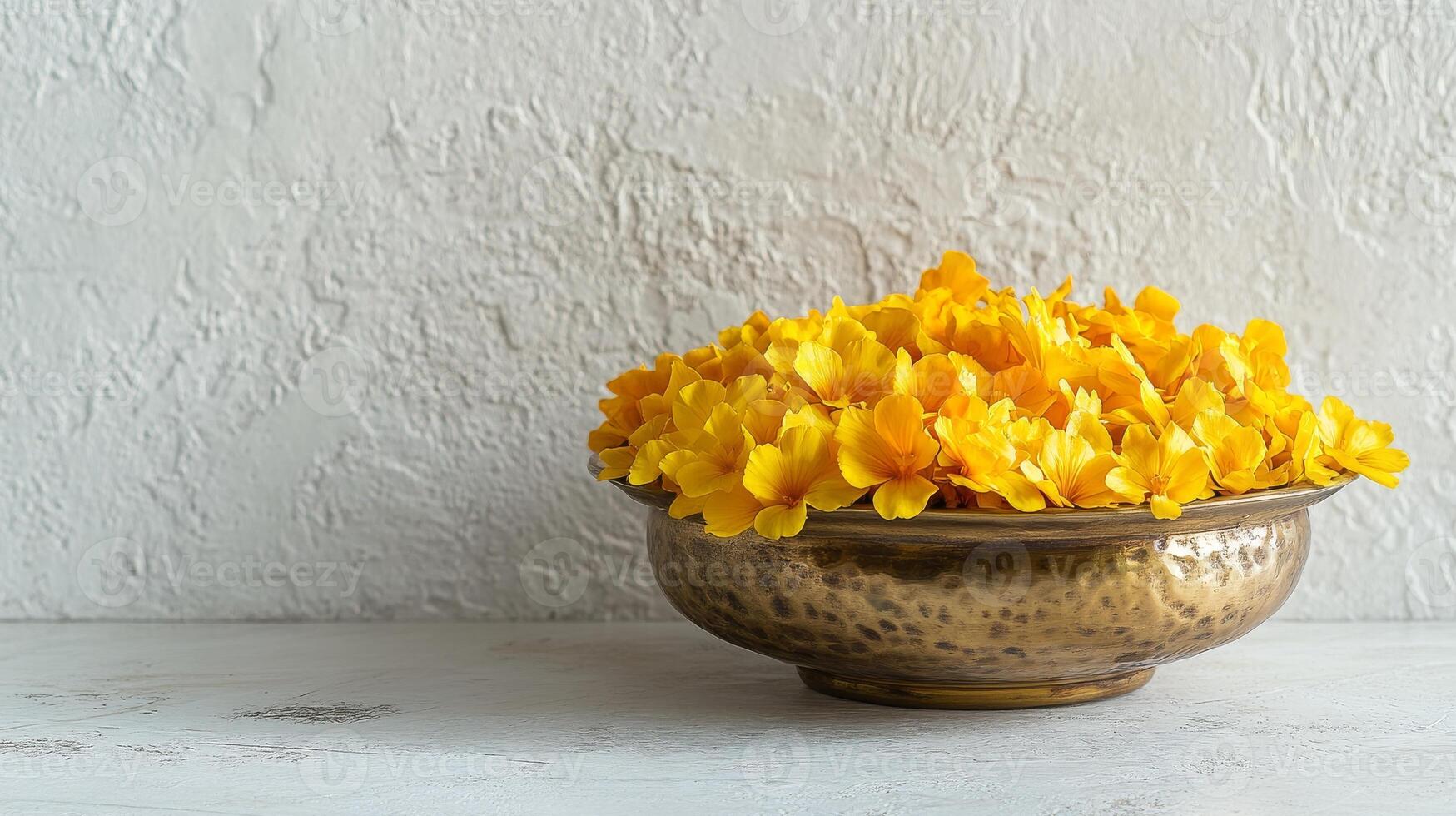 Minimalist arrangement of golden yellow flowers in hammered brass bowl for elegant decor.Vishu day photo