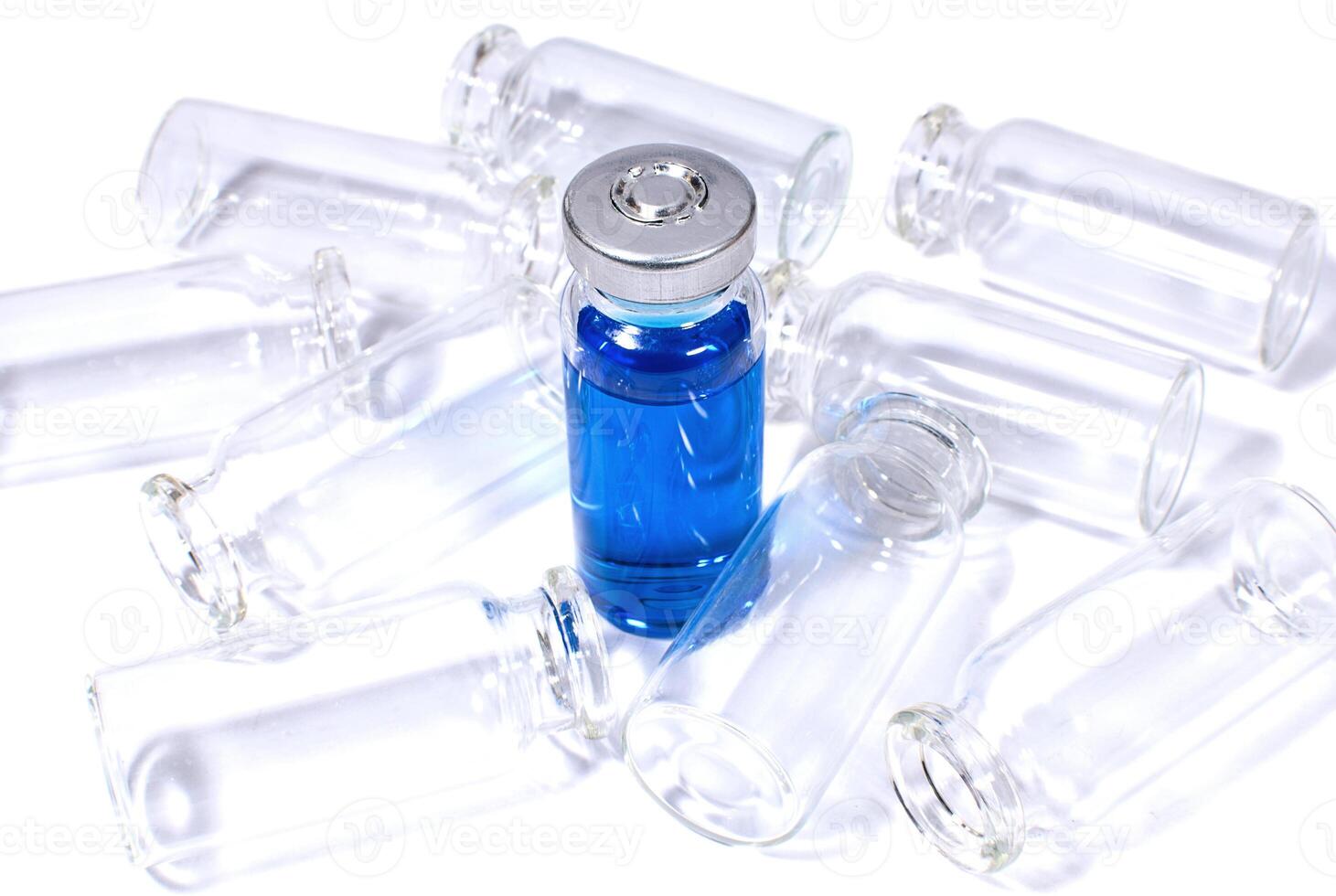 Flacon with blue vaccine and heap of empty bottles photo
