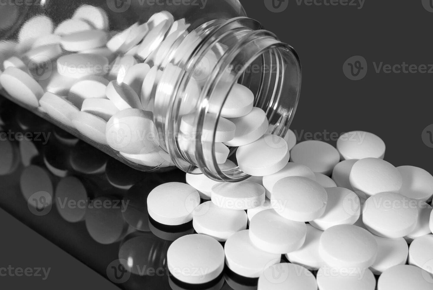 White pills falling out of a transparent plastic bottle photo