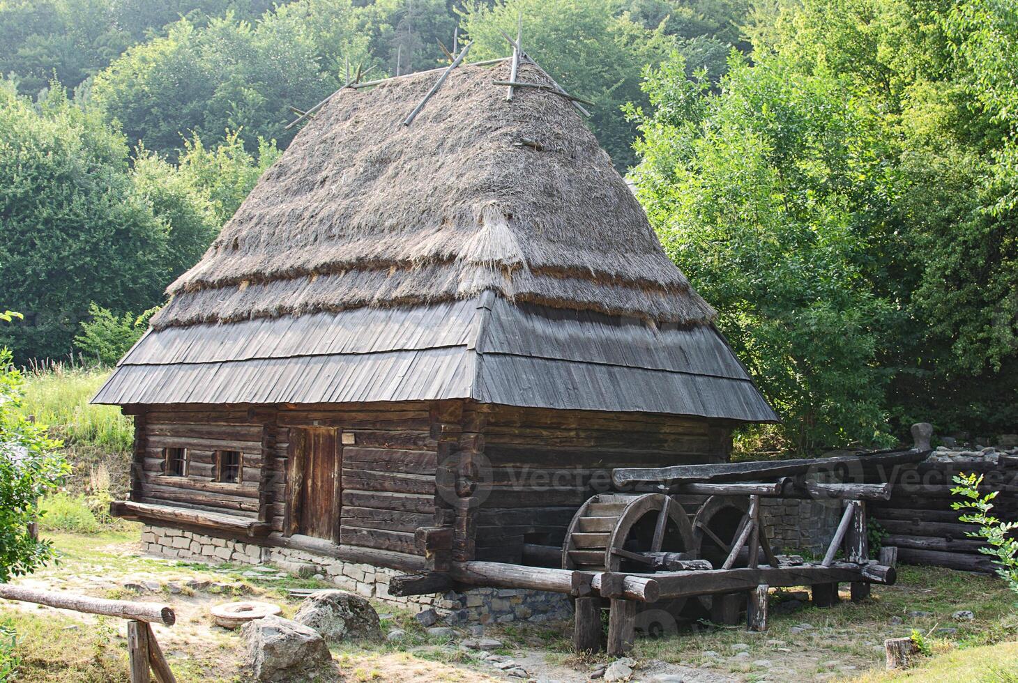 Old water mill on the background of green trees photo
