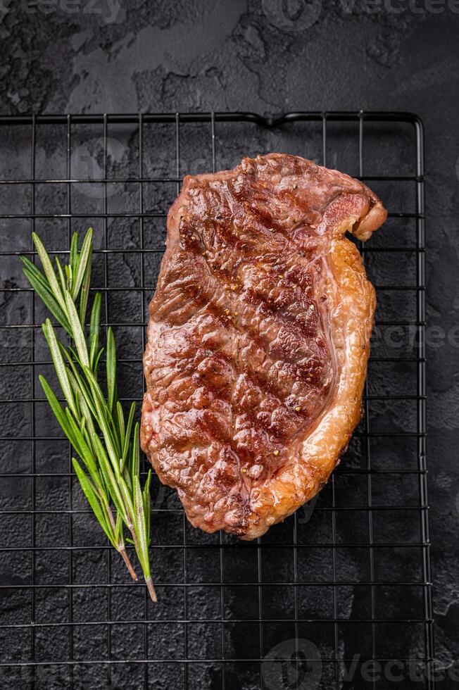 Juicy grilled striploin New York steak with perfect grill marks, ideal for a hearty meal or summer barbecue. black background. top view photo