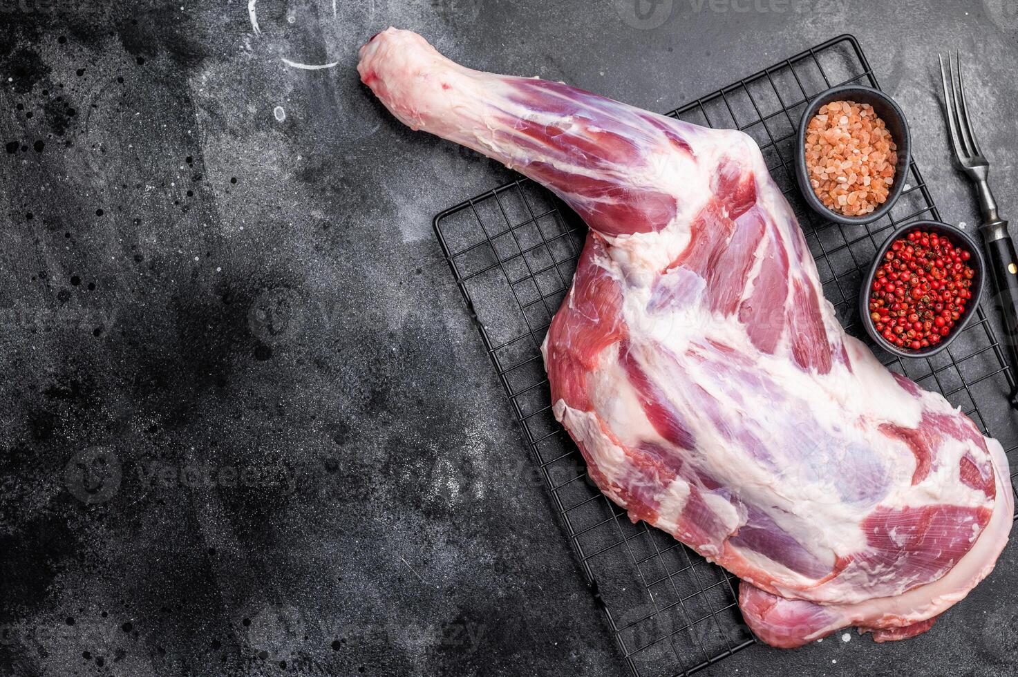 Fresh raw lamb shoulder, leg perfect for slow cooking or roasting to create a tender, flavorful meal. black background. top view photo