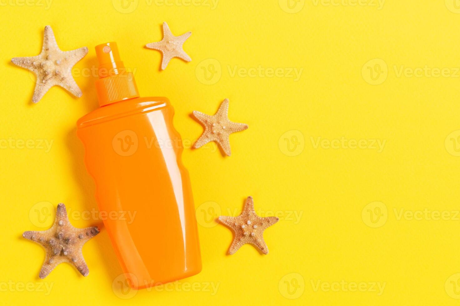 sunscreen cream with starfishells in bottles on yellow background, top viewsh and sea photo