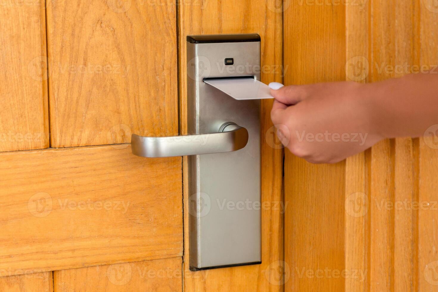 Female hand putting holding magnetic key card switch in to open hotel room door photo