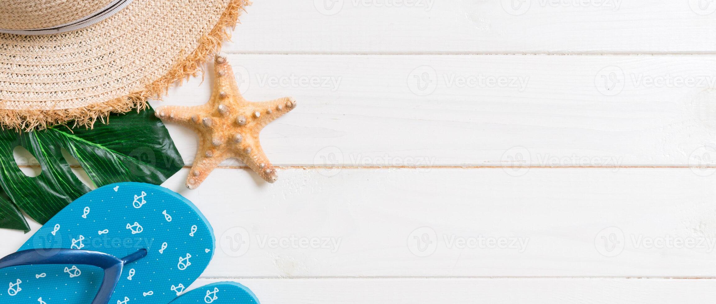 Straw hat, green leaf, blue flip flops and starfish On a white wooden background. banner top view summer holiday concept with copy space photo