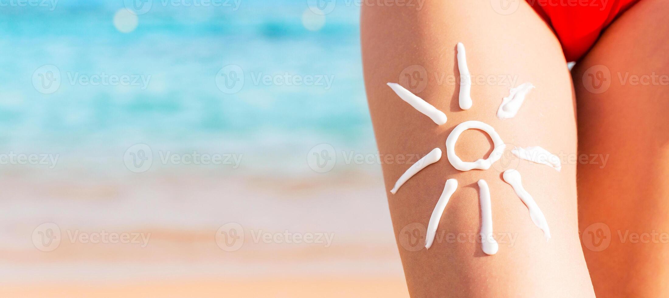 Sun shape is made of sunscreen on woman's leg at the sea background photo