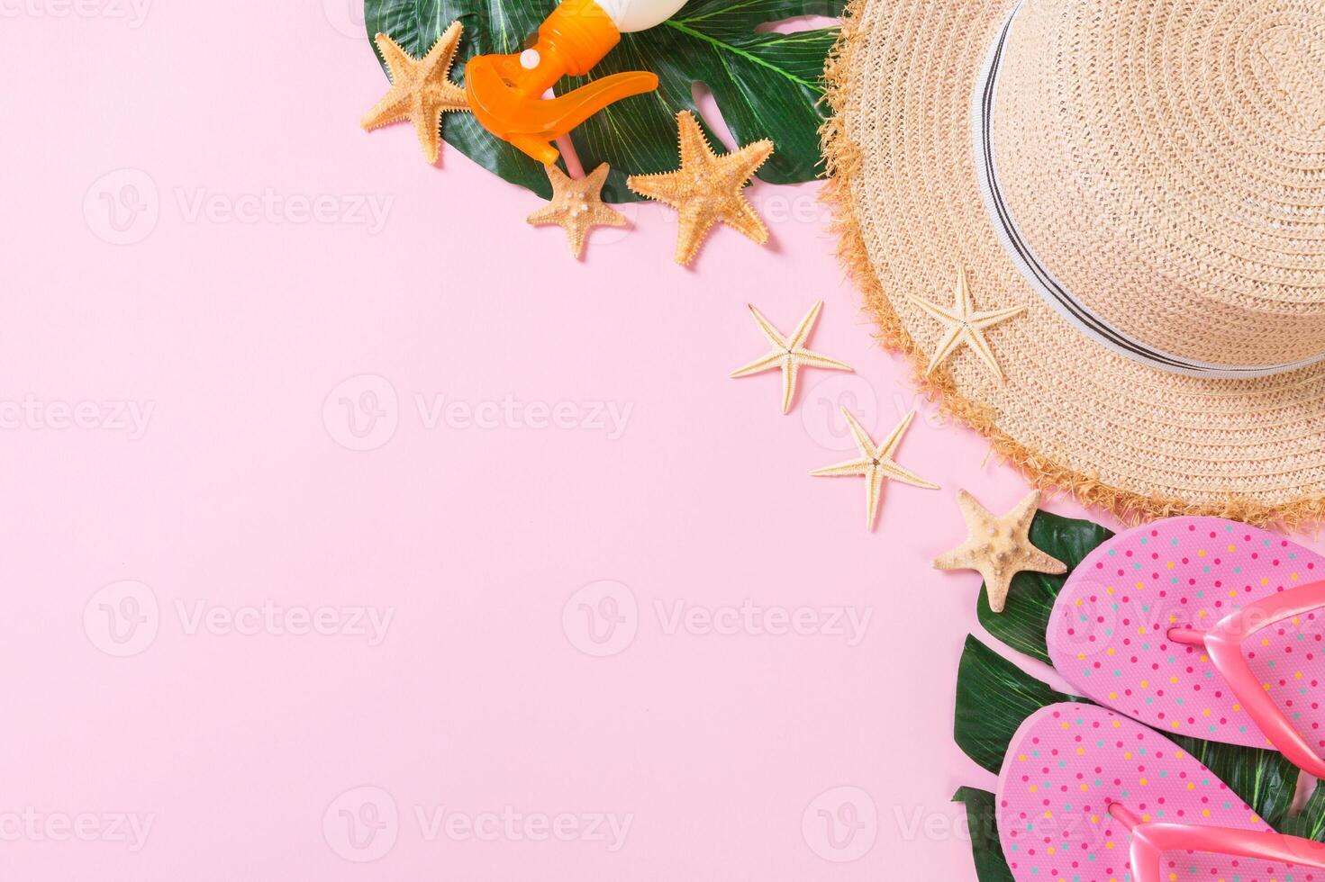 Beach accessories with straw hat, sunscreen bottle and seastar on pink background top view copy space photo