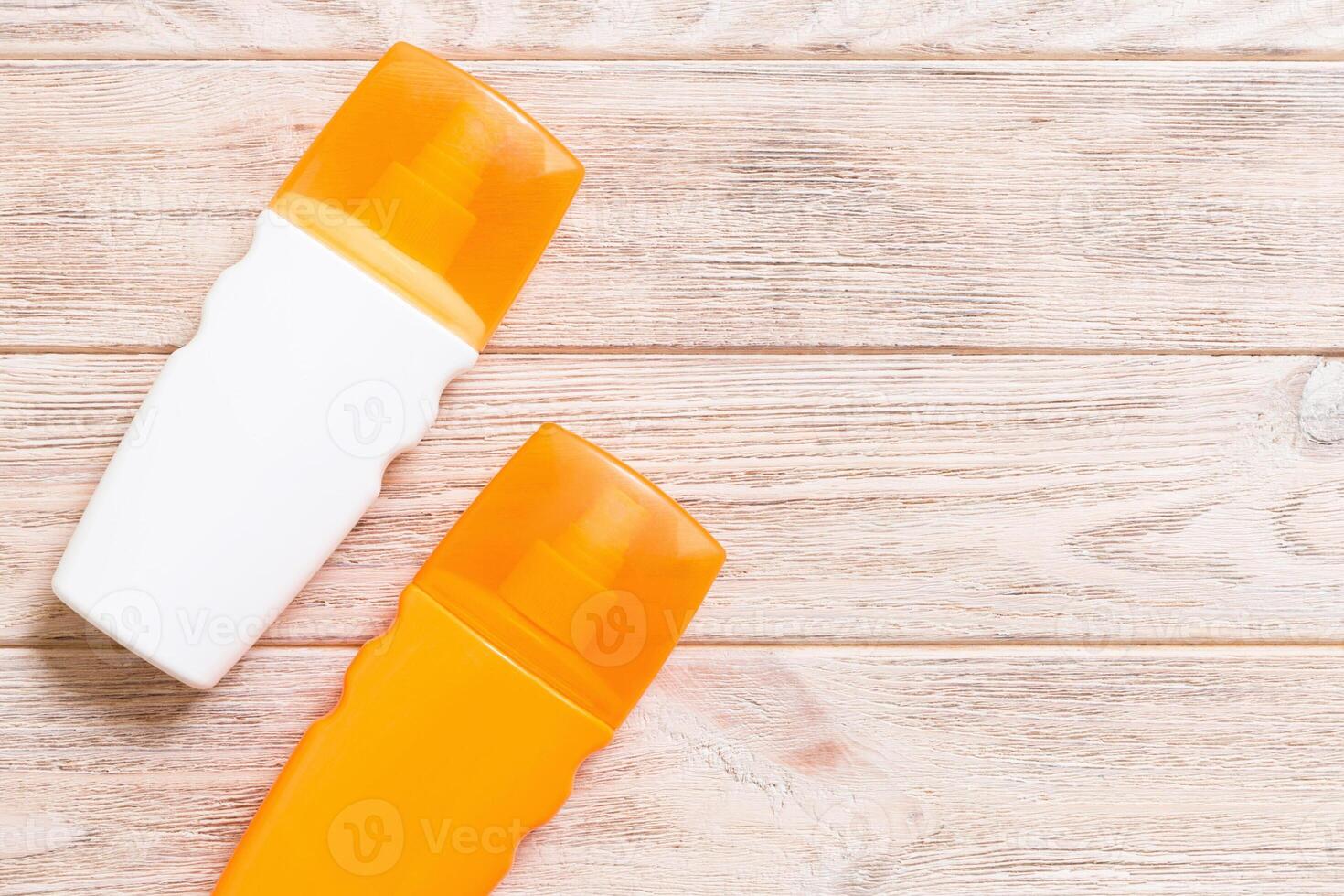 Two Sunscreen bottles on bright wooden background, top view with copy space photo