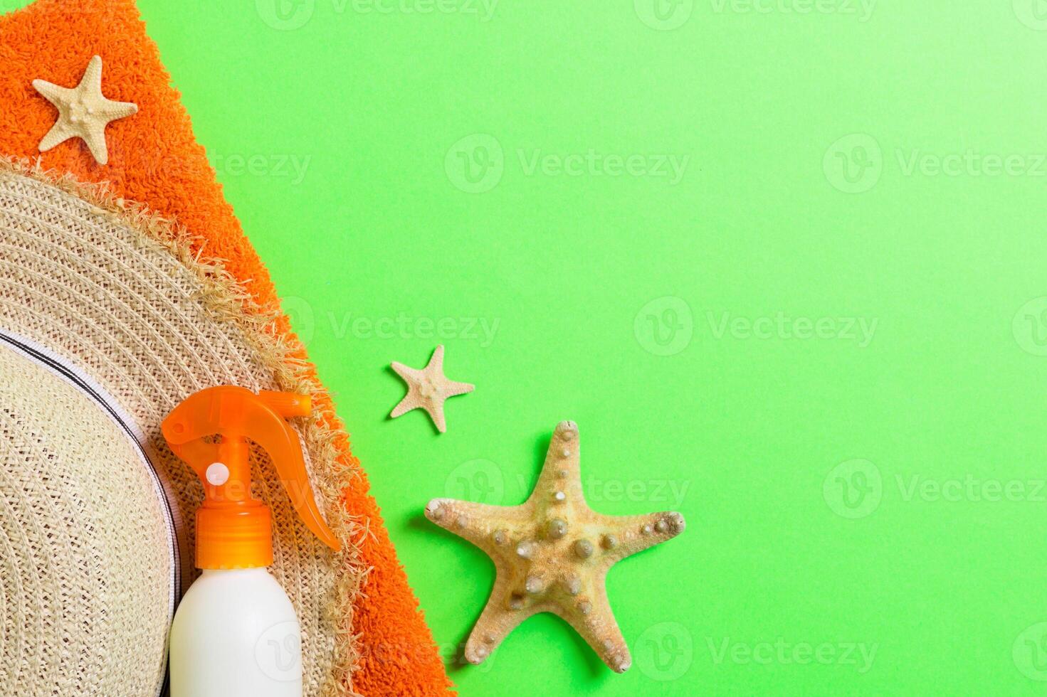 Summer beach flat lay accessories. Sunscreen bottle cream, straw hat, towel and seashells on colored Background. Travel holiday concept copy space photo