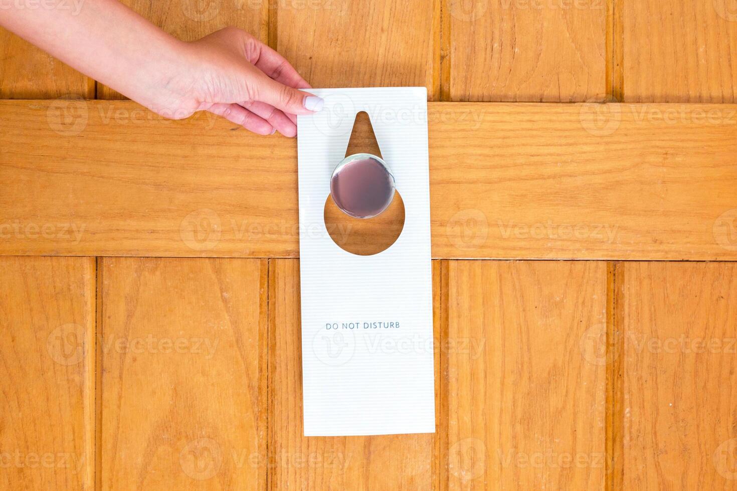 Woman hand holding hangs signboard do not disturb on the door in hotel photo