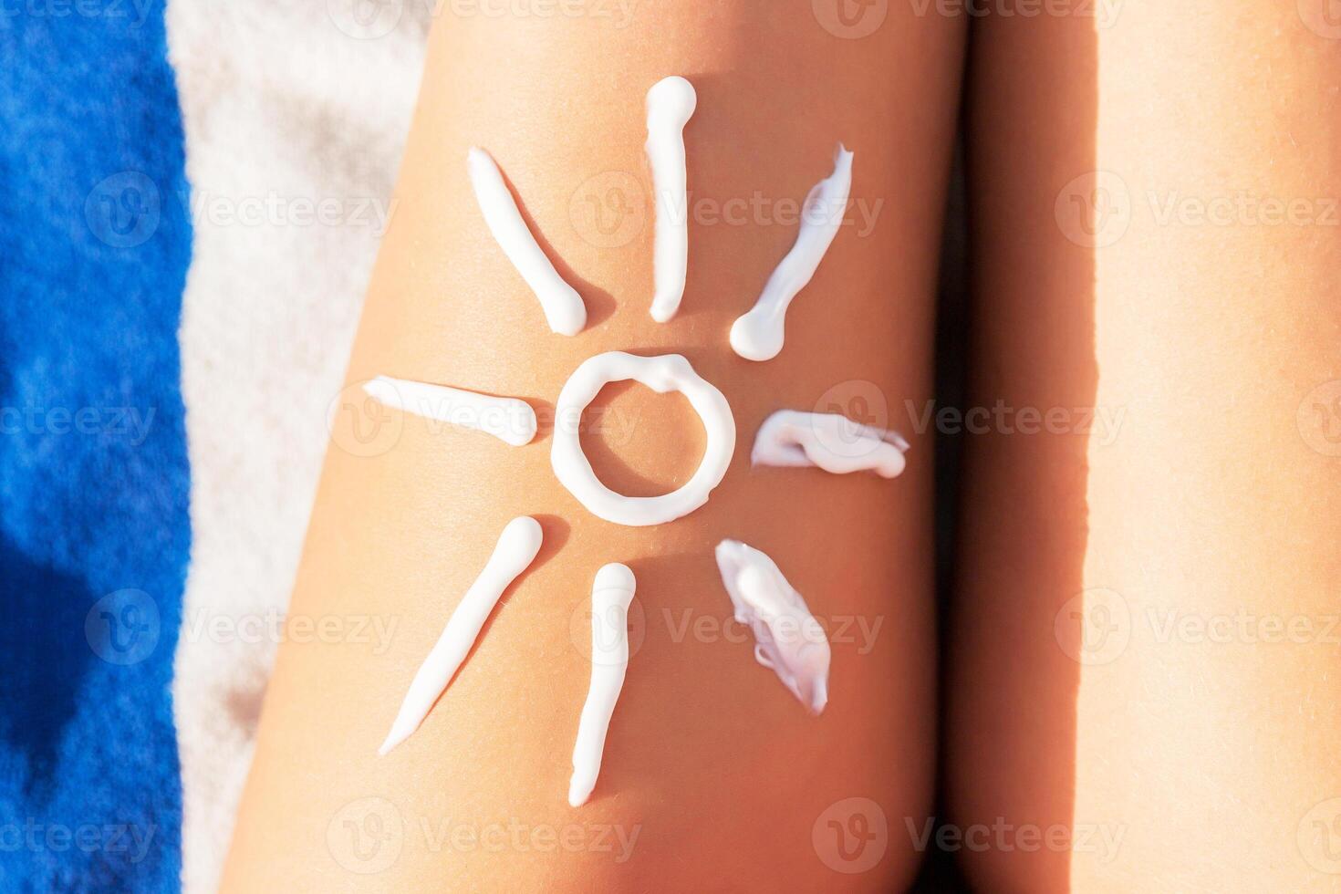 Woman sunbathing the beach with drawing of sun on her leg with sunscreen cream photo