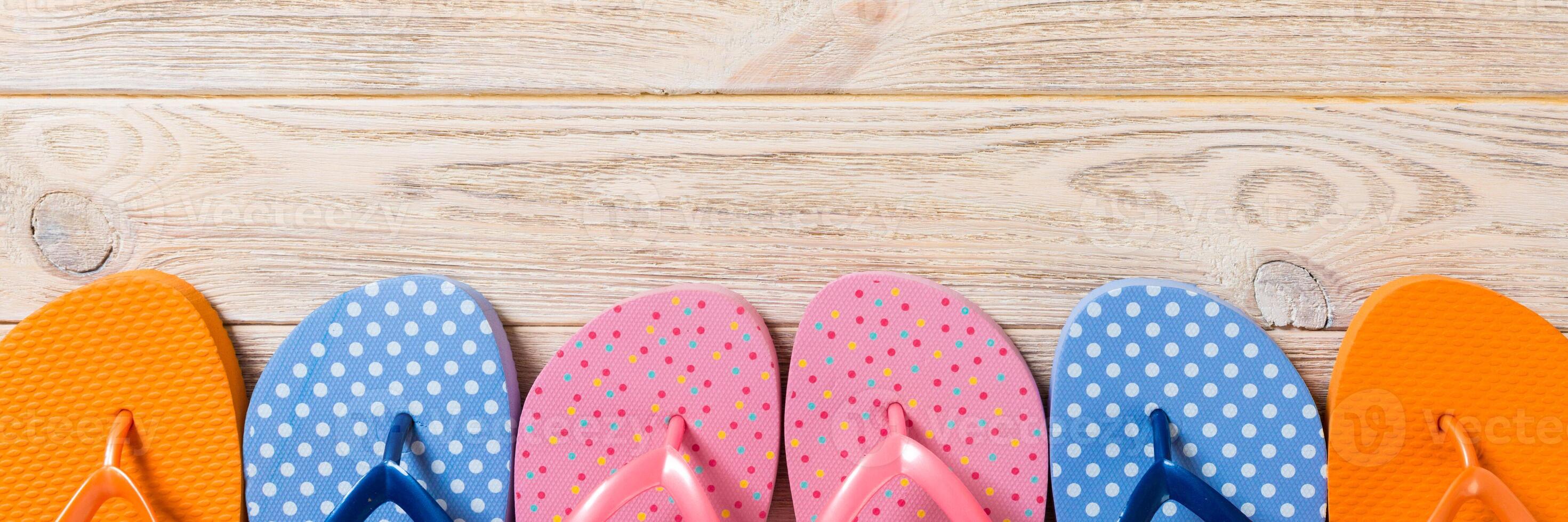 a lot of flip flop colored sandals, summer vacation on wooden background, banner copy space top view photo