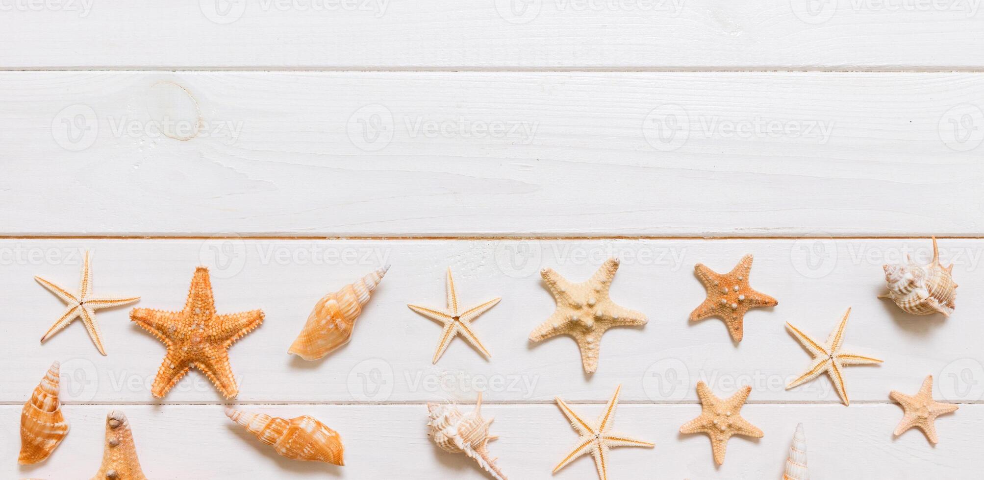 Summertime wooden table with starfish and seashells on a white background banner top view. Copy space background, summer concept photo