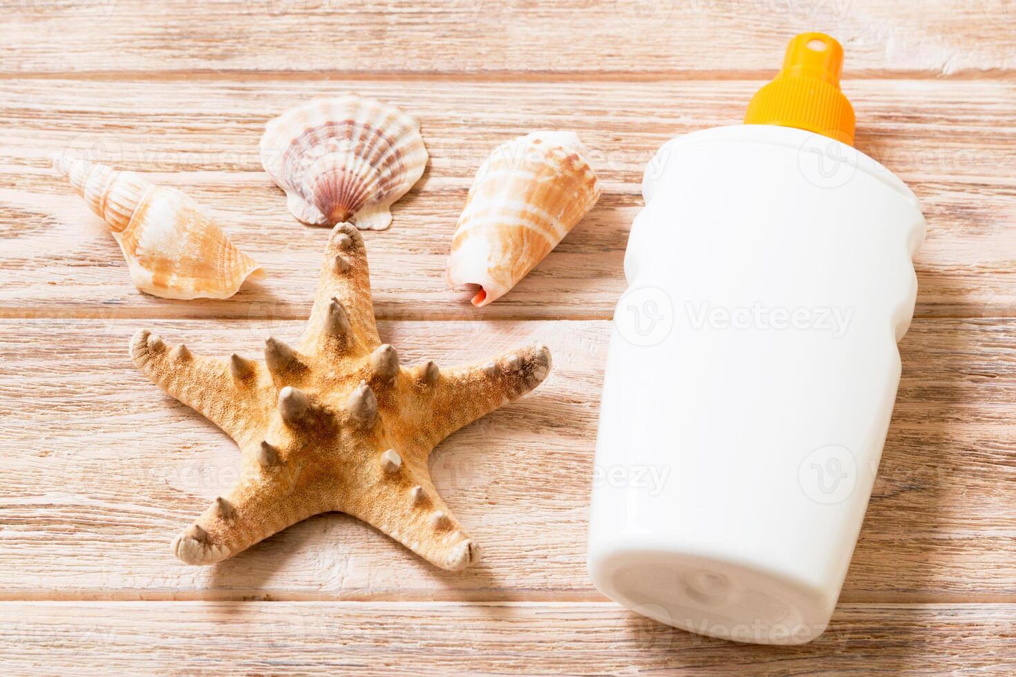 Sunscreen bottles with seashells and starfish on wooden table flat lay concept summer travel vacation photo