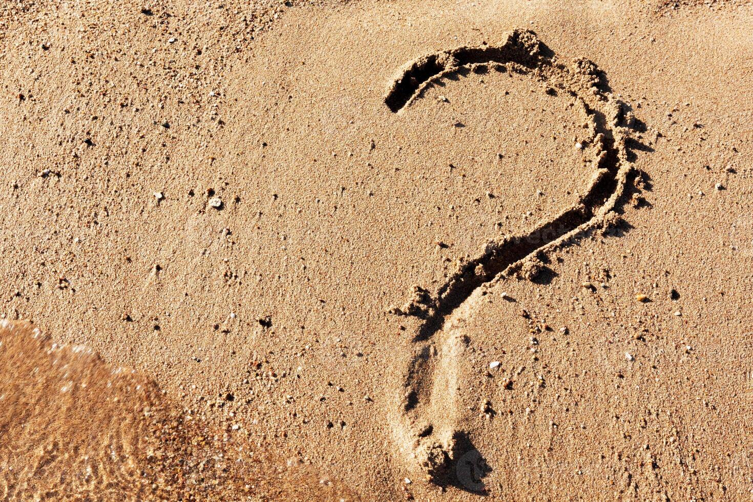 Question mark sign sand beach near the sea. Concept of dilemma, answer and question photo