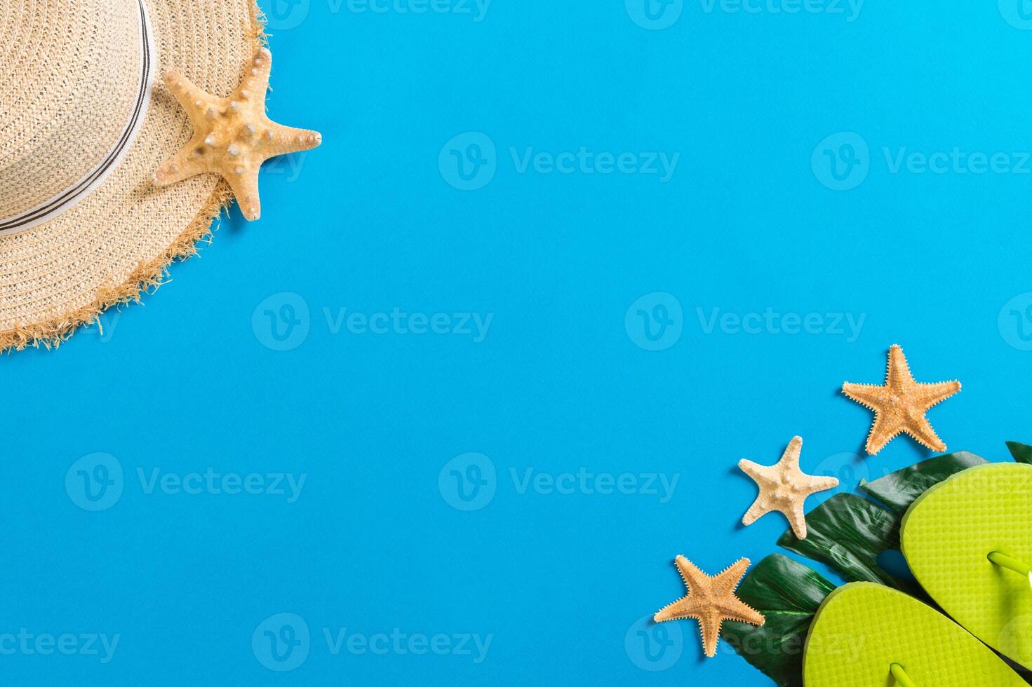 Beach accessories with straw hat and seashells blue background top view with copy space photo