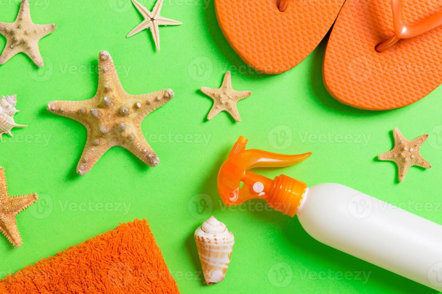 Top view Beach flat lay accessories. sunscreen bottle with seashells, starfish, towel and flip-flop Colored background copy space photo