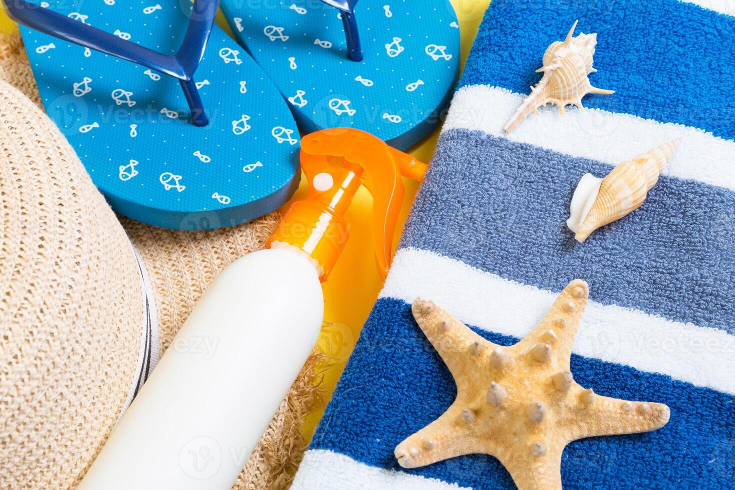 flip flops, straw hat, starfish, sunscreen bottle, body lotion spray yellow background top view . flat lay summer beach sea accessories background, holiday concept photo