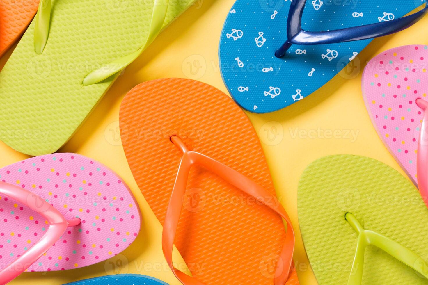 many colored flip flops yellow background. Copy space top view photo