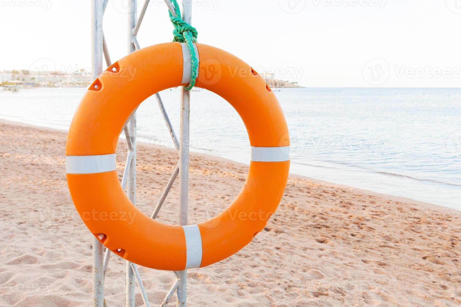 Orange lifebuoy lifeguard tower on blue sky and beach background photo