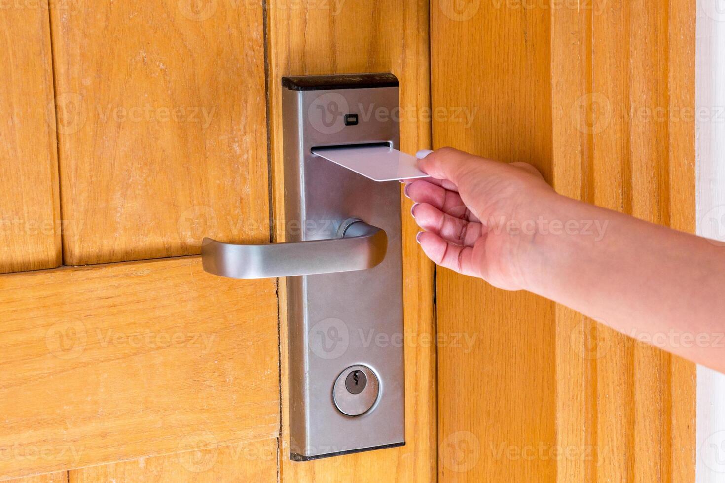 Female hand putting and holding magnetic key card switch in open hotel room door photo