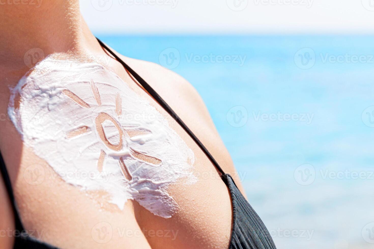 Sun shaped sunscreen woman's breast over sea background photo