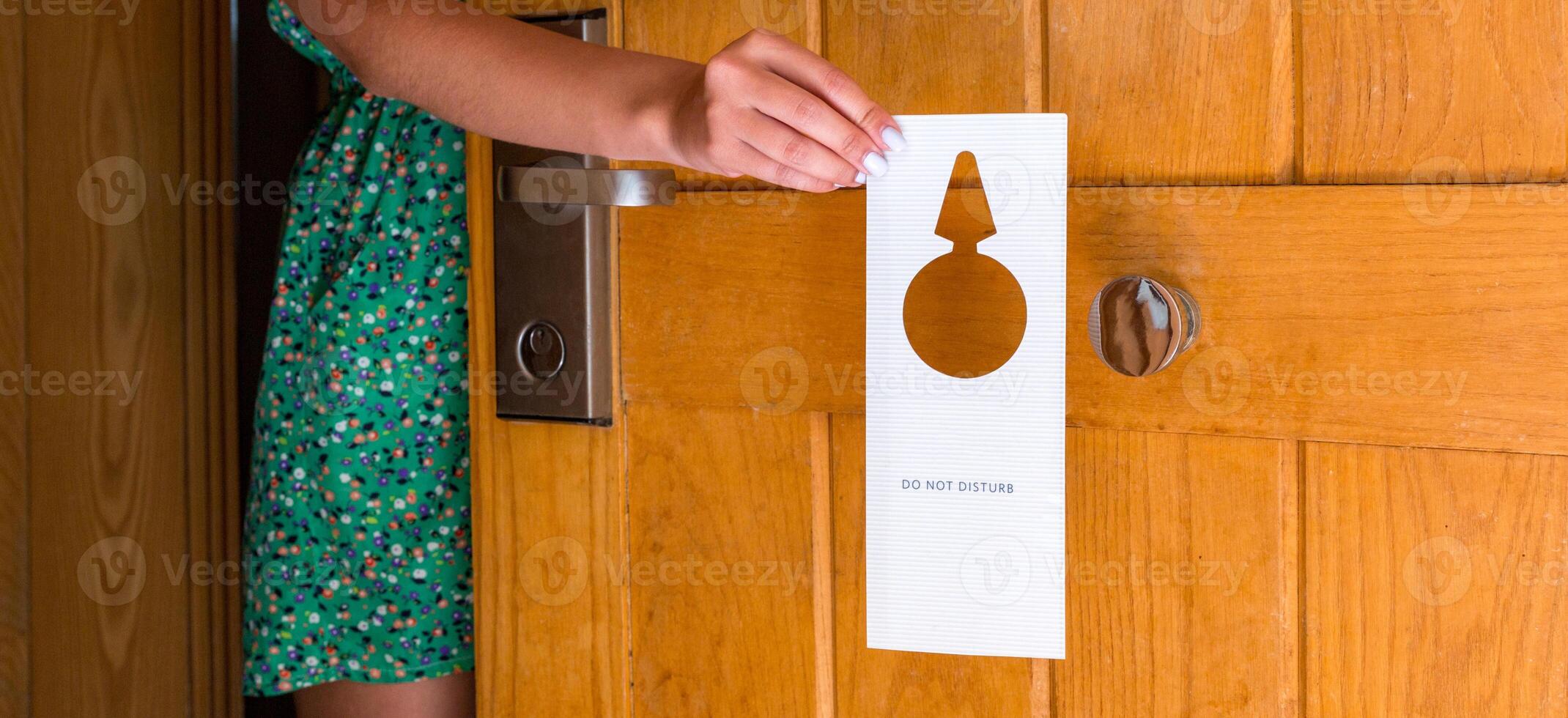 female hand hangs sign on the door do not disturb in hotel photo