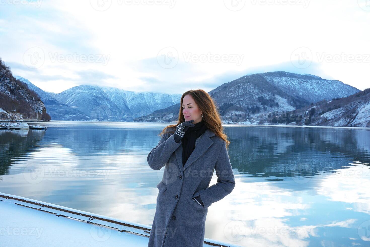Thoughtful woman by snowy fjord and mountains in Gaupne, Norway winter scene photo