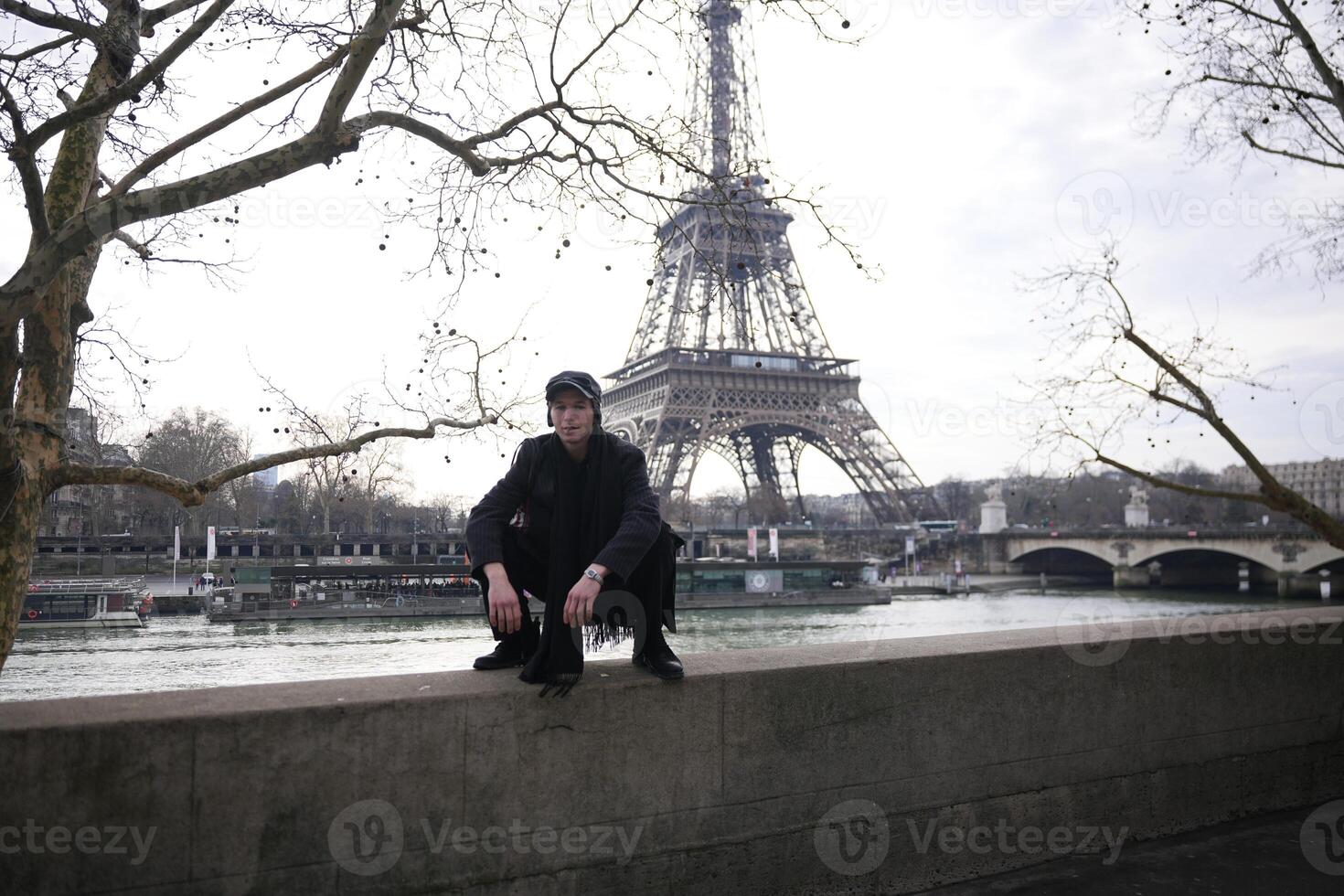 Man in black squatting near Eiffel Tower on winter day photo