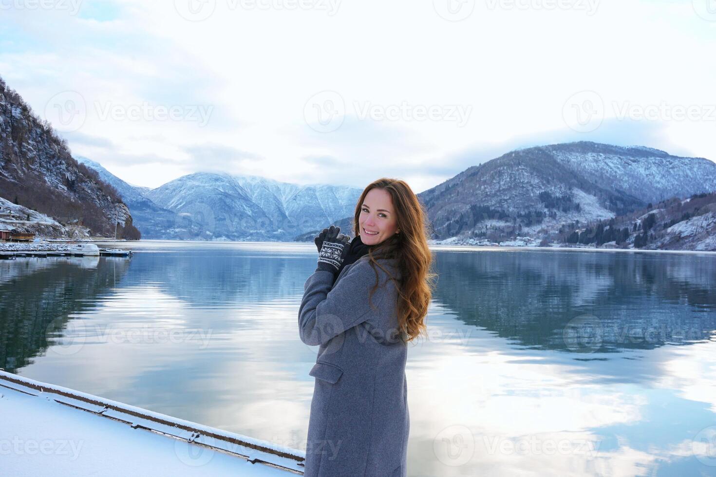 Smiling woman by snowy fjord and mountains in Gaupne, Norway winter landscape photo