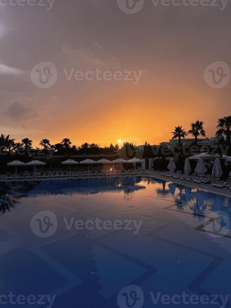 Luxury resort pool at sunset with palm trees photo