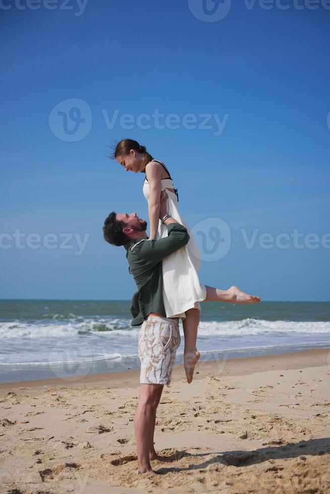 Happy couple enjoying romantic moment on sunny beach during summer vacation photo