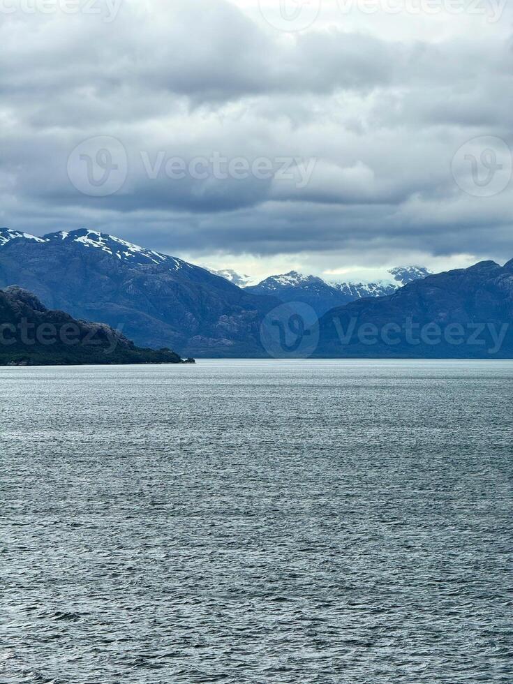 Snow-Capped Mountains and Deep Fjord Under Cloudy Sky in Remote Wilderness photo