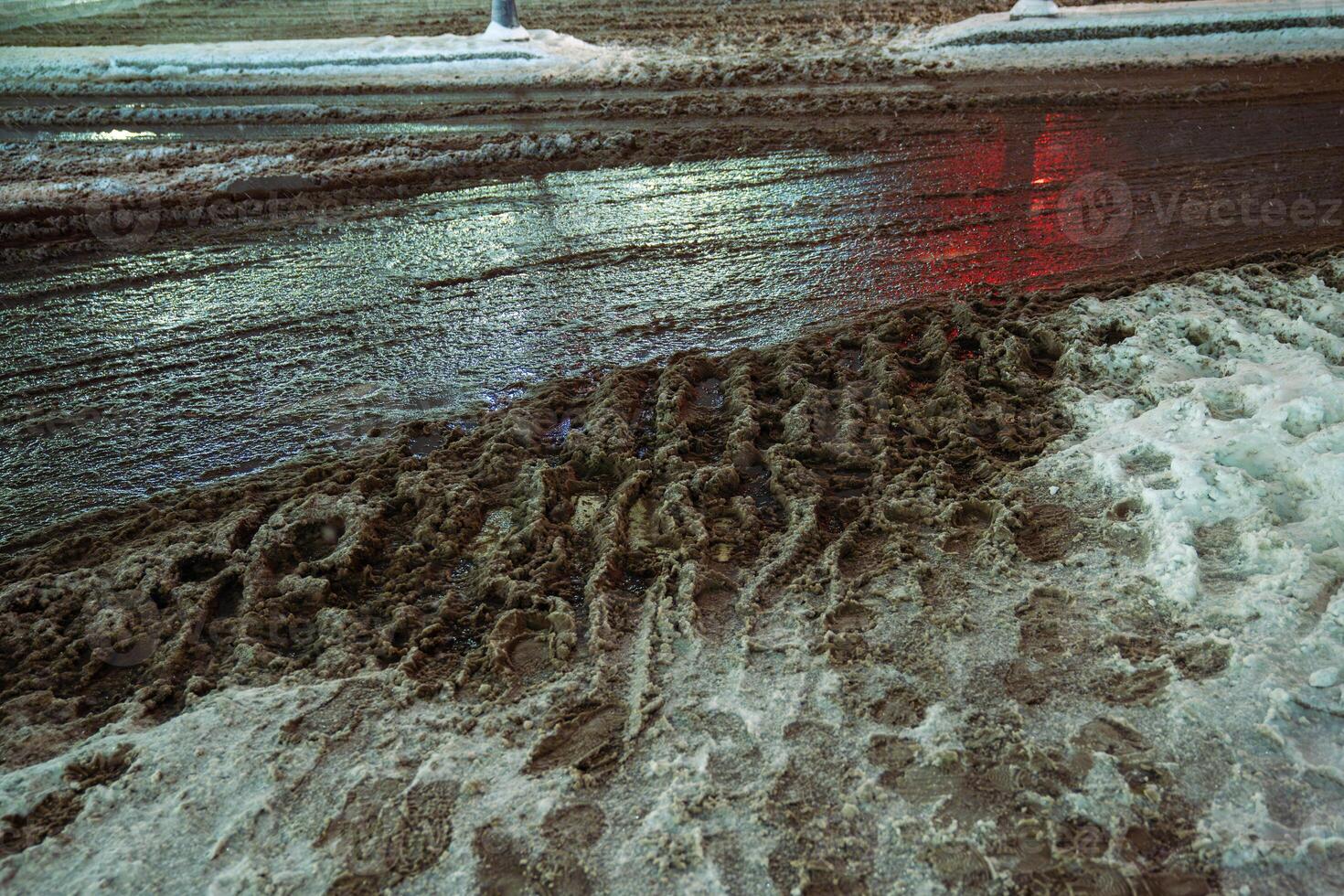 Snowfall followed by thaw, slushy snow and dirt cover roads as salt melt snow into muddy slush photo
